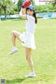 A woman in a white dress holding a baseball glove.