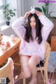 a woman sitting on top of a wooden chair next to a table