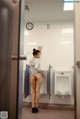 A woman standing in front of a urinal in a public restroom.