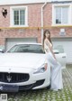 A woman in a white dress standing next to a white car.