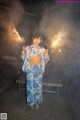 A woman in a kimono holding sparklers in her hands.