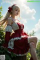 A woman in a red and white dress sitting on a tree stump.