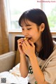 A woman sitting on a bed eating a piece of food.