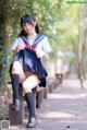 A woman in a school uniform sitting on a bench.