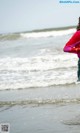 A woman standing on the beach with her back to the camera.