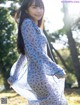 A woman in a blue dress standing in a park.