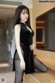 A woman in a black dress is posing for the camera.