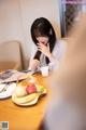 A woman sitting at a table with a plate of fruit.