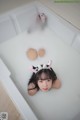 A woman laying in a bathtub with her feet in the water.