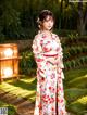 A woman in a kimono standing in a garden.