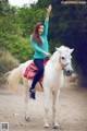 A woman riding on the back of a white horse.