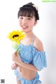 A young girl holding a sunflower in her hand.