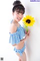 A young girl holding a sunflower in her hand.