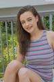 A young woman sitting on a porch with her legs crossed.