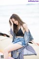 A woman sitting on top of a boat on the beach.