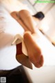 A close up of a woman's feet in high heels on a bed.