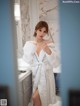 A woman in a white robe standing in a bathroom.