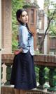 A woman in a blue shirt and black skirt standing on a balcony.