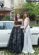 Two women standing next to a white car.