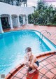 A little girl sitting on the edge of a swimming pool.