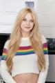 A woman with long blonde hair wearing a rainbow sweater.