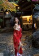 A woman in a red kimono standing in front of a building.